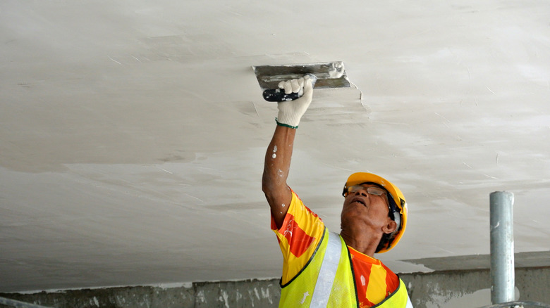 Şantiyede tavana skim ceket çalışması uygulayan inşaat işçisi