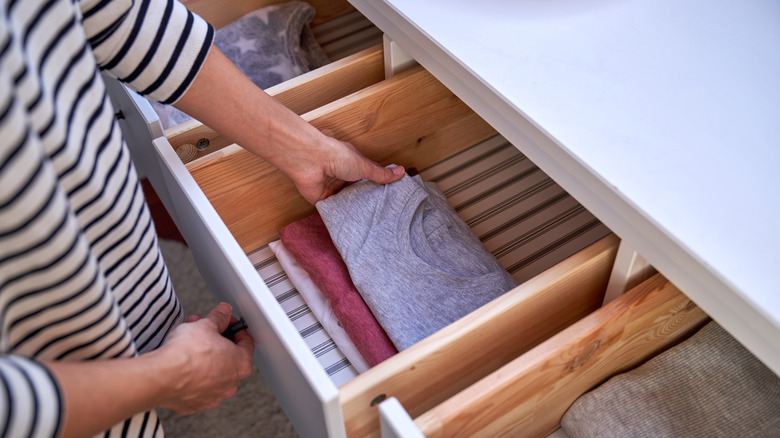 Çizgili bir çekmeceye ulaşan bir kadın