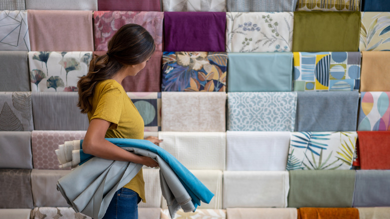 Bir mağazadaki farklı kumaşlara bakan kişi