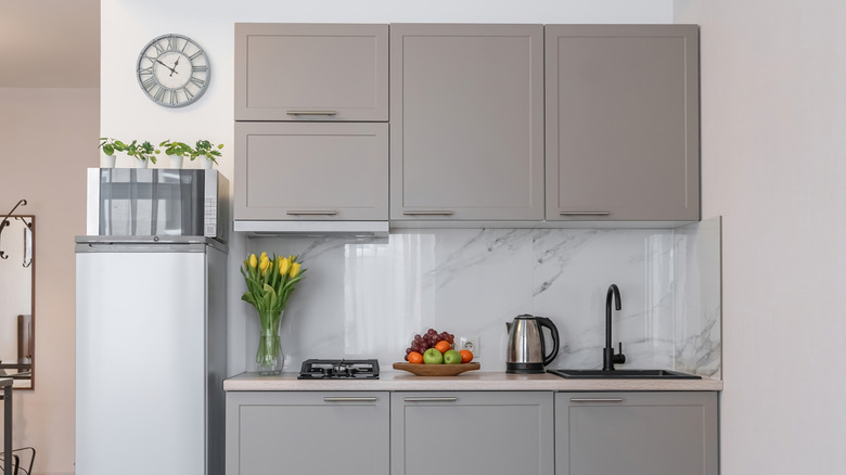 Graycabinets ve lavabonun yanında mikrodalga ile küçük buzdolablı mutfak alanı