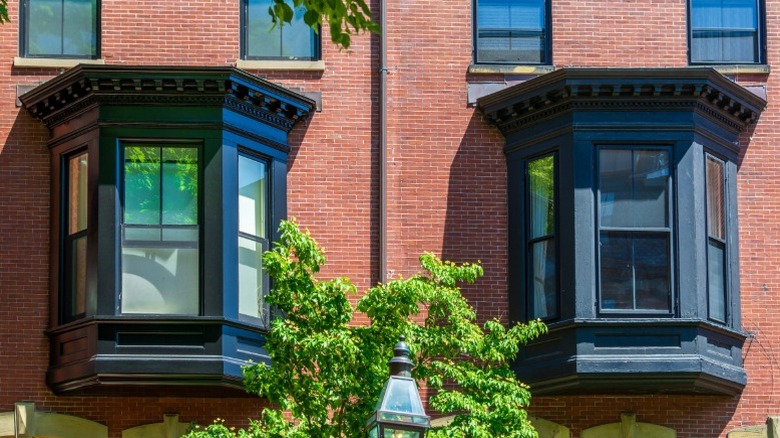 Bir tuğla binanın genişliğinde iki süslü siyah oriel penceresi