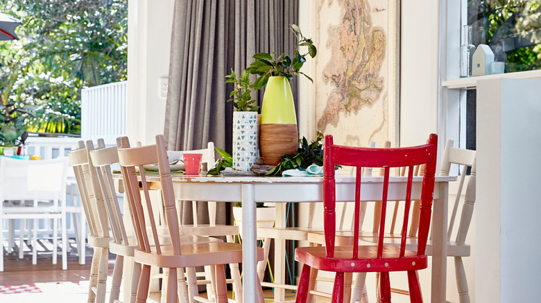 Beyaz, ahşap masa, kırmızı sandalye ile ahşap sandalyeler ve duvarda bir harita ile Shaby Chic yemek odası.