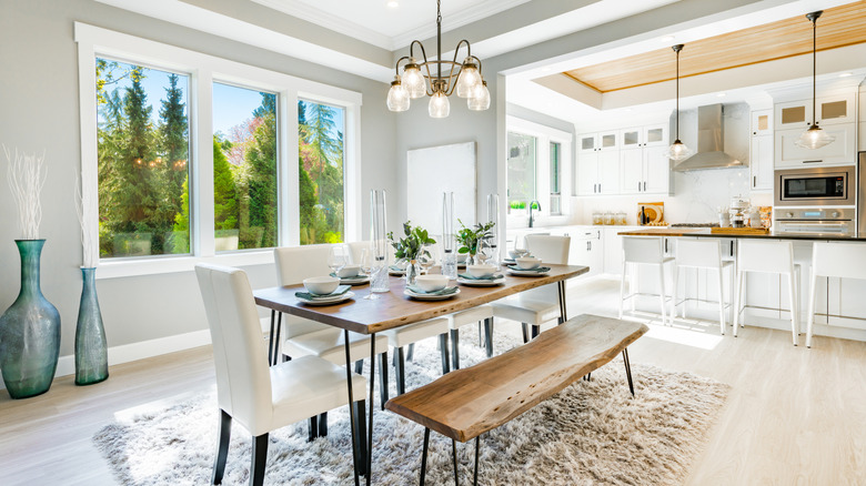 Ahşap masa ve tezgah ve beyaz döşemeli sandalyeler ile çiftlik evi yemek odası.