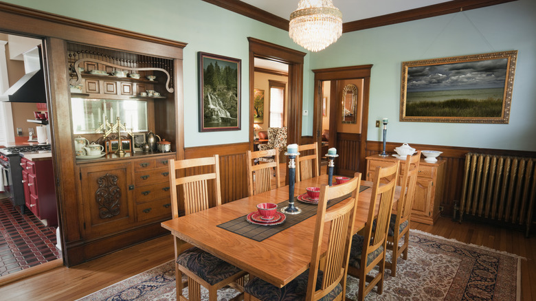 Ahşap masa ve eşleşen sandalyeler, manzara sanatı, yerleşik bir dolap ve bir avize ile Victoria yemek odası.