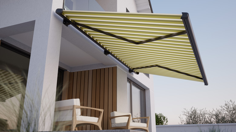 Açık oturma alanının üstünde çizgili yeşil tente