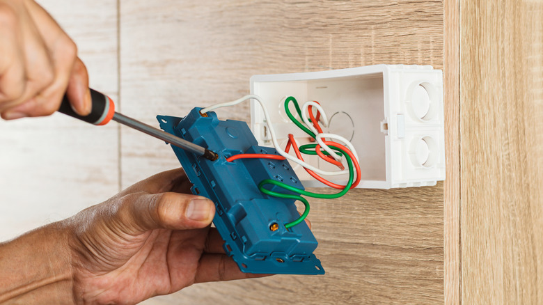 Elektrikçi bir kabinin içine bir çıkış kutusu takıyor