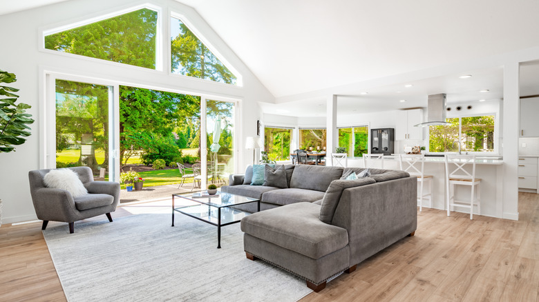 Geniş bir açık plan yaşam alanı ve güneşli bir bahçeye bakan büyük pencerelere sahip mutfak.