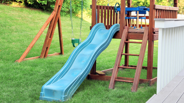 Bir bahçede slayt ve salınımlı ahşap bir tırmanma çerçevesi.