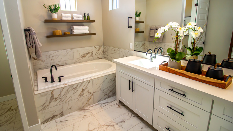 Küçük küvet ve lavabolu mermer bir banyo.