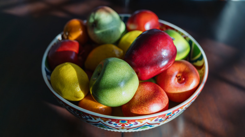 Farklı renk ve tonlarda elmalarla dolu bir meyve kasesi.