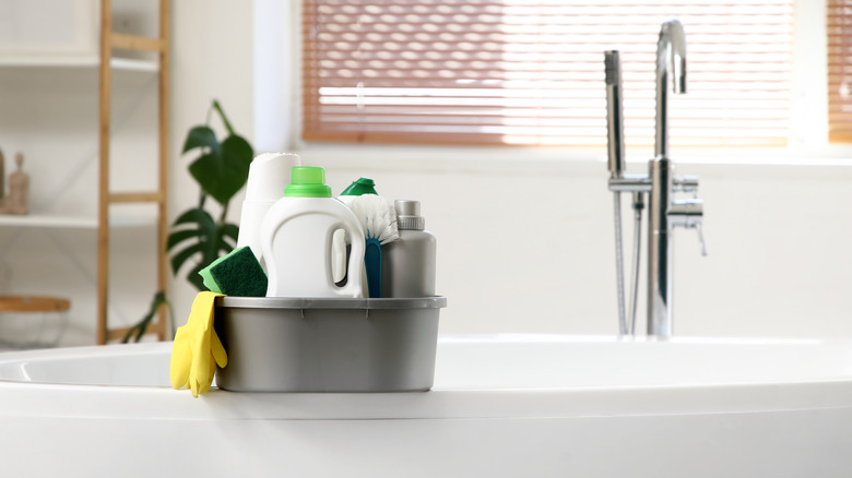 Çeşitli temizlik ürünleri ile bir küvetin kenarında caddy temizleme