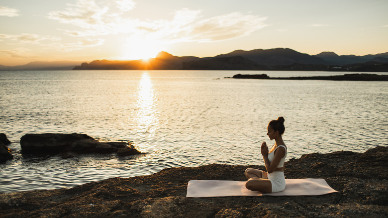 Gün batımı sırasında adada yoga yapıyor kadın