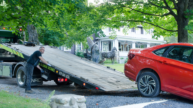 Kırmızı bir sedan çeken adam