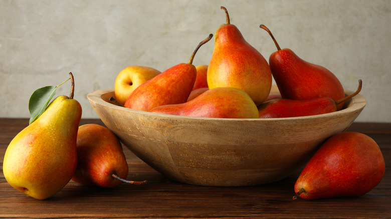 Bir mutfak tezgahı veya masa üstü üzerinde ahşap bir kapta olgunlaşan armutlar.