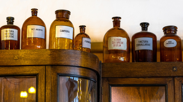 Ahşap kabine dizilmiş antika kehribar kavanozlar