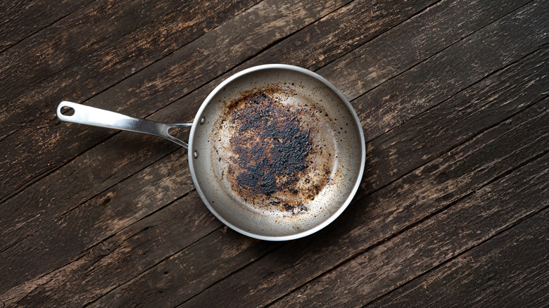 koyu ahşap bir masada kirli alüminyum tava