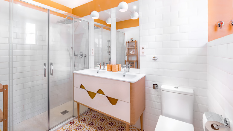 Portakal, beyaz ve kahverengi döşeme ve tuvalet tarafından retro bir ahşap lavabo ile modern bir banyo.