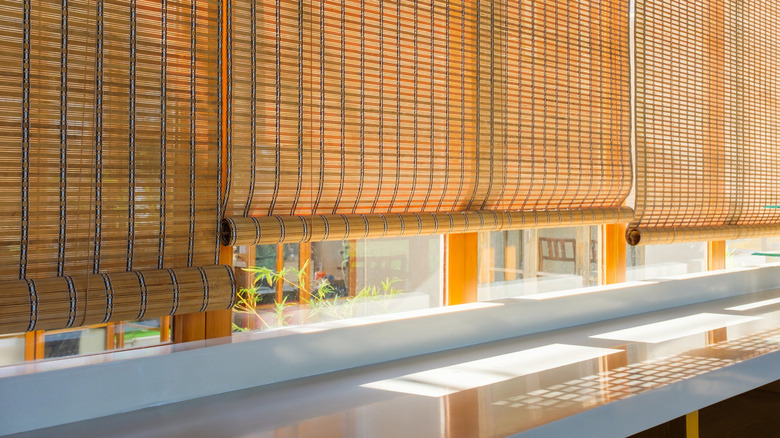 Bambu panjurlar güneşi pencerelerin duvarında kısmen bloke eder.