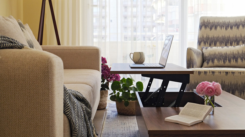 Dizüstü bilgisayar ve ayarlanabilir bir sehpanın yükseltilmiş tepesinde kupa