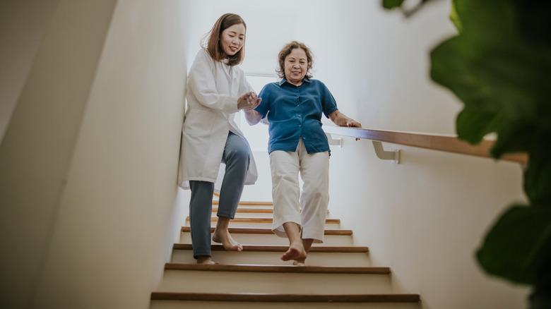 Yaşlılara merdivenden aşağı yardım eden kişi