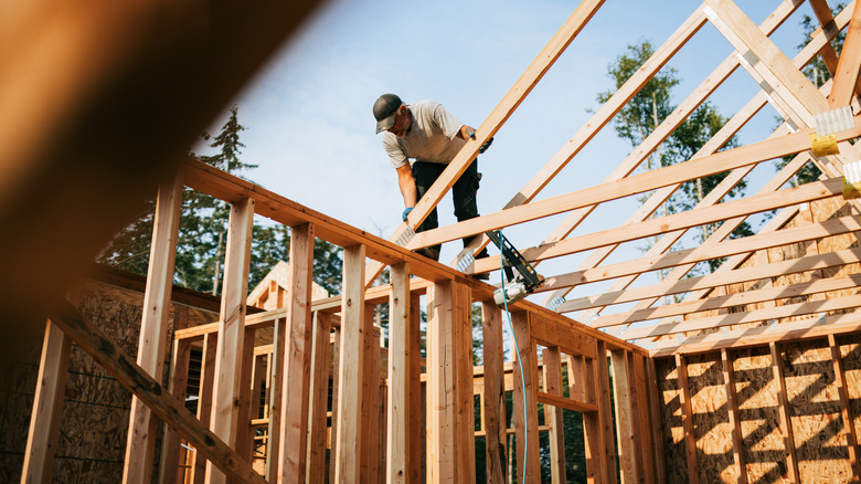 Adam bir çatıya kafesleri koyuyor, bir ev inşa ediyor
