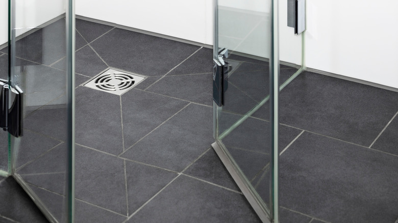 Krom drenajı ve cam kapıları açılan siyah kiremitli bir duş zemini