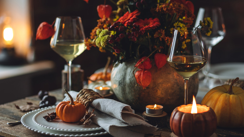 Portakal kabakları ve çiçeklerle bir sonbahar masa manzarası.