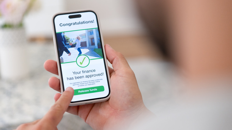 Ekranda kredi onayı ile akıllı telefon tutan kişi