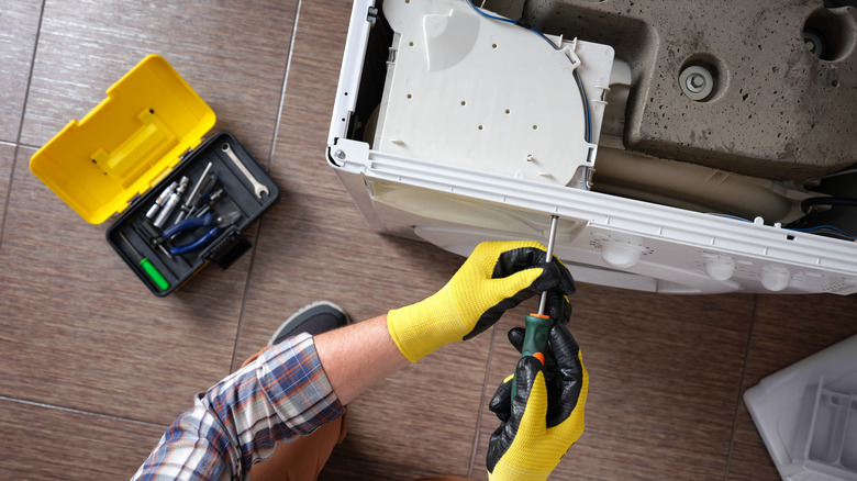 Tornavida bir cihazı sabitleyen bir tamirci.