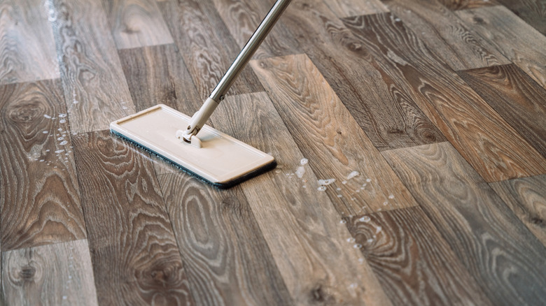 Su ve sabun kabarcıkları ile sahte ahşap laminat zeminde bir paspas.