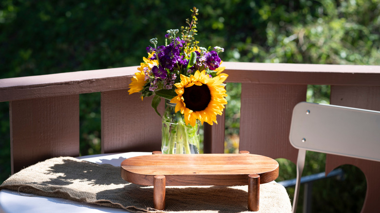 Güneş ışığında açık bir masada oturan çiçeklerle top mason kavanozu