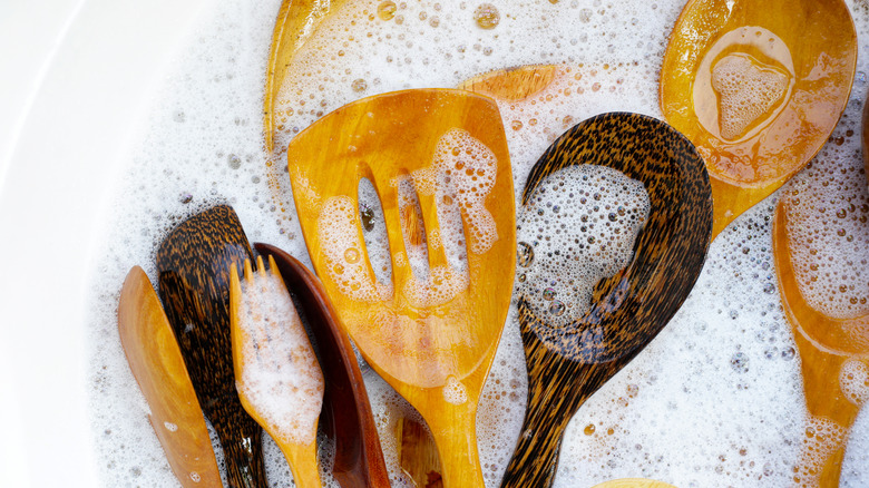 Ahşap mutfak eşyaları sıcak, sabunlu suda oturuyor