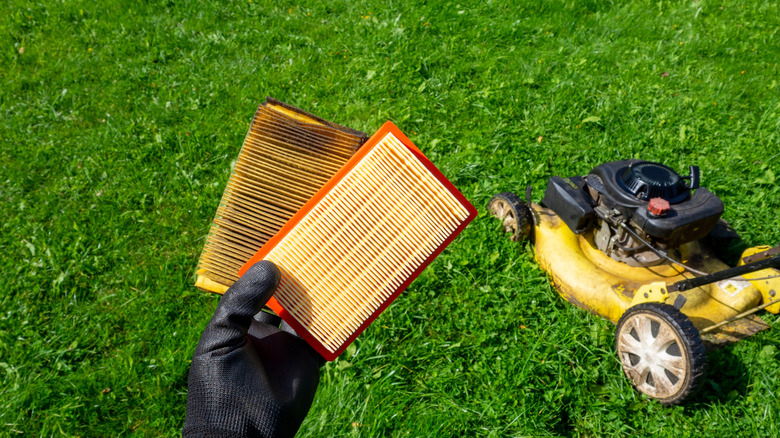 Çim biçme makinesi hava filtrelerine bakan kişi