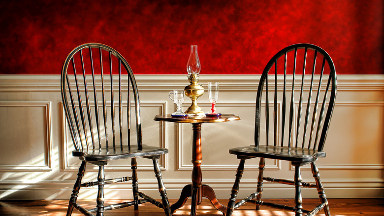 Kırmızı sahte boyalı duvar kaplamasının önünde ahşap sandalyeler ve masa