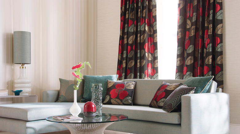 Bir kanepenin atma yastıklarına uyan koyu yaprak desenli perdeler