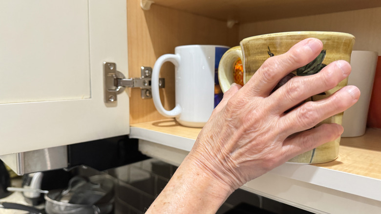 Kabinden bir kahve kupası tutan bir el.