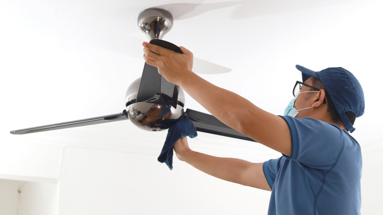 Mikrofiber bir bezle fan bıçaklarını silerek adam