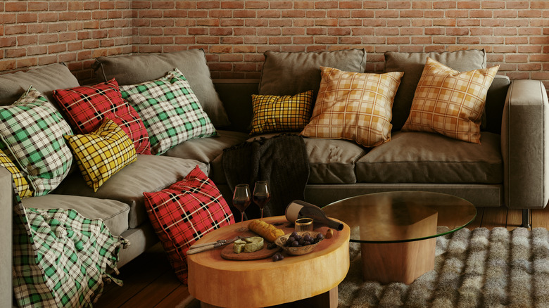 Sehpaların yanındaki gri bir kanepede ekose yastıklar.