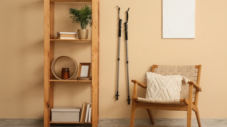 Bir raf ve sandalyenin yanındaki bir duvara karşı kayak direkleri.