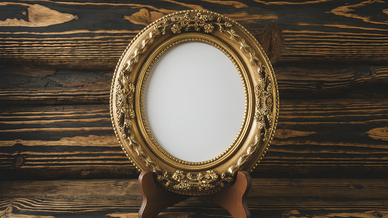 Ahşap standında eski bir altın resim çerçevesi.