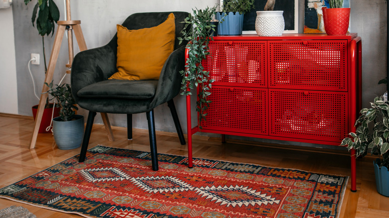 Siyah bir sandalye ve kırmızı mobilya parçasının altında oryantal halı.