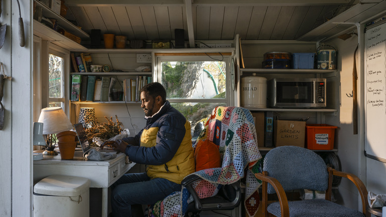 Bir adam sıkışık bir kulübenin içindeki bir masaya oturur