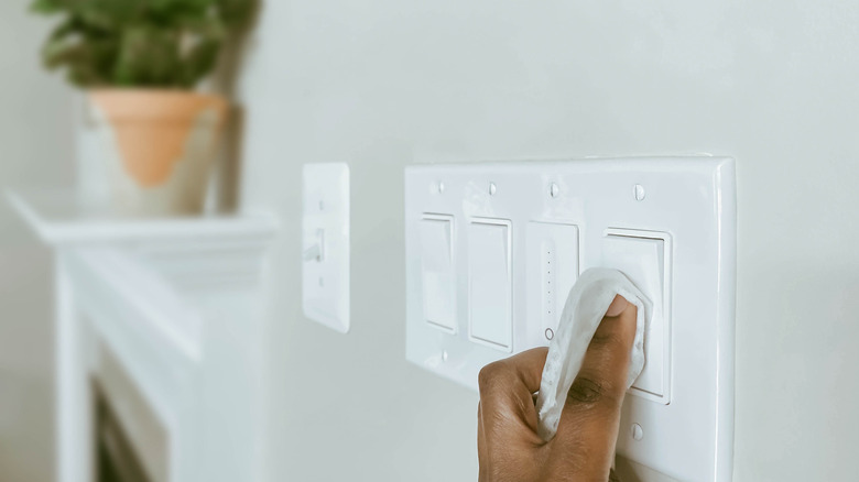 Bir ışık anahtarını temizleyen kadının elini kapatın