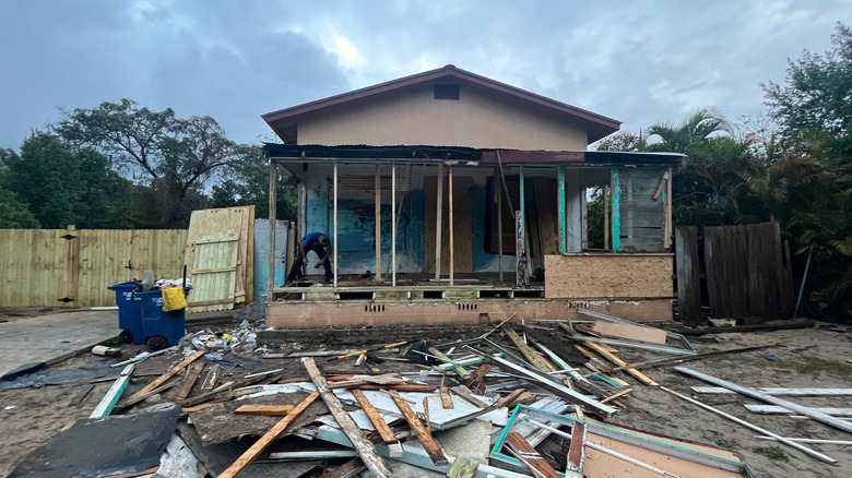 Bir adam bir kasırga tarafından ciddi şekilde hasar gören bir evi onarmaya başlar