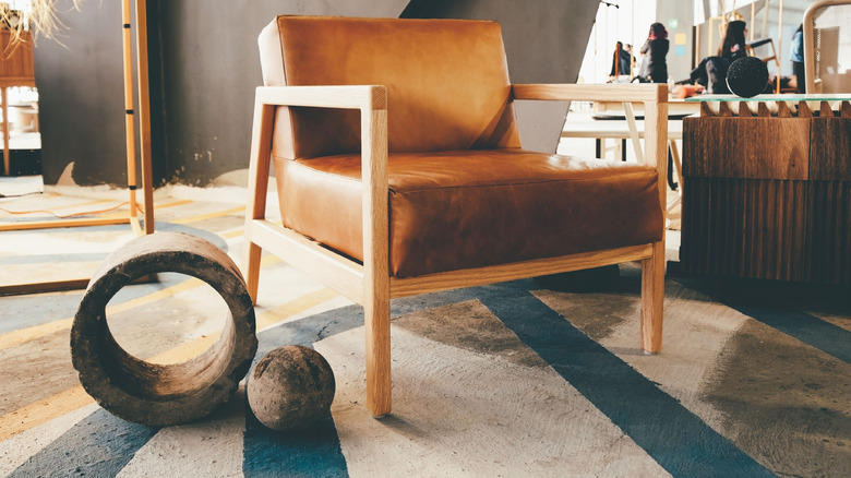 İki dekoratif taş nesnenin yanında, beton bir zeminde deri koltuk yakın çekimi