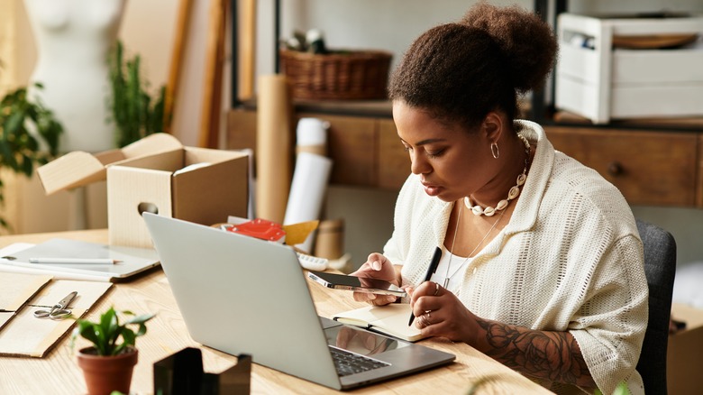 Telefon ve dizüstü bilgisayar kullanırken satın alma araştırması yapan kadın