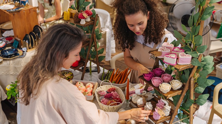 El sanatları fuarındaki kadınlar satıcının sattığı ürünleri tartışıyor