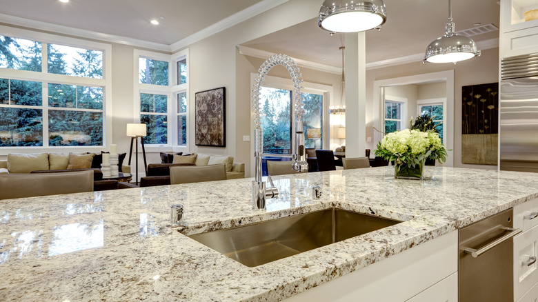 Büyük beyaz mutfakta benekli granit tezgahlar bulunur