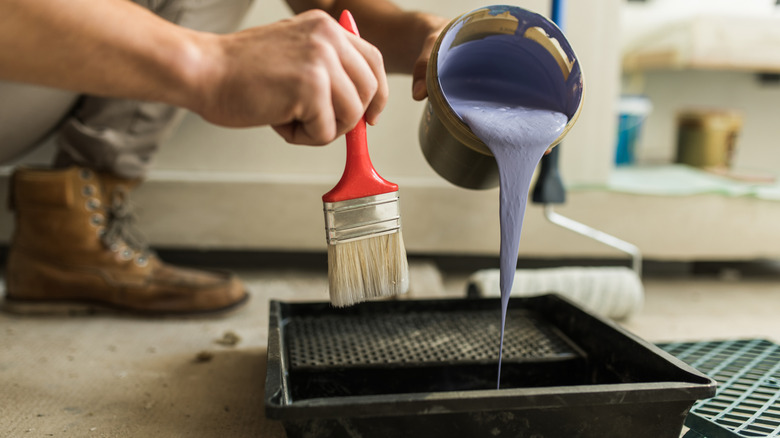 Kişi sürgülü dolap kapısını süslemeden önce mor boya döküyor.