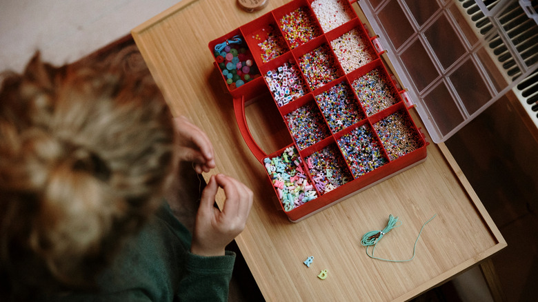 Birisi kırmızı takım kutusundan boncuk çıkarıyor.